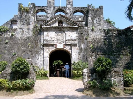 The coral-stone gateway of Fort San Pedro, visitors walking in under its carved arch