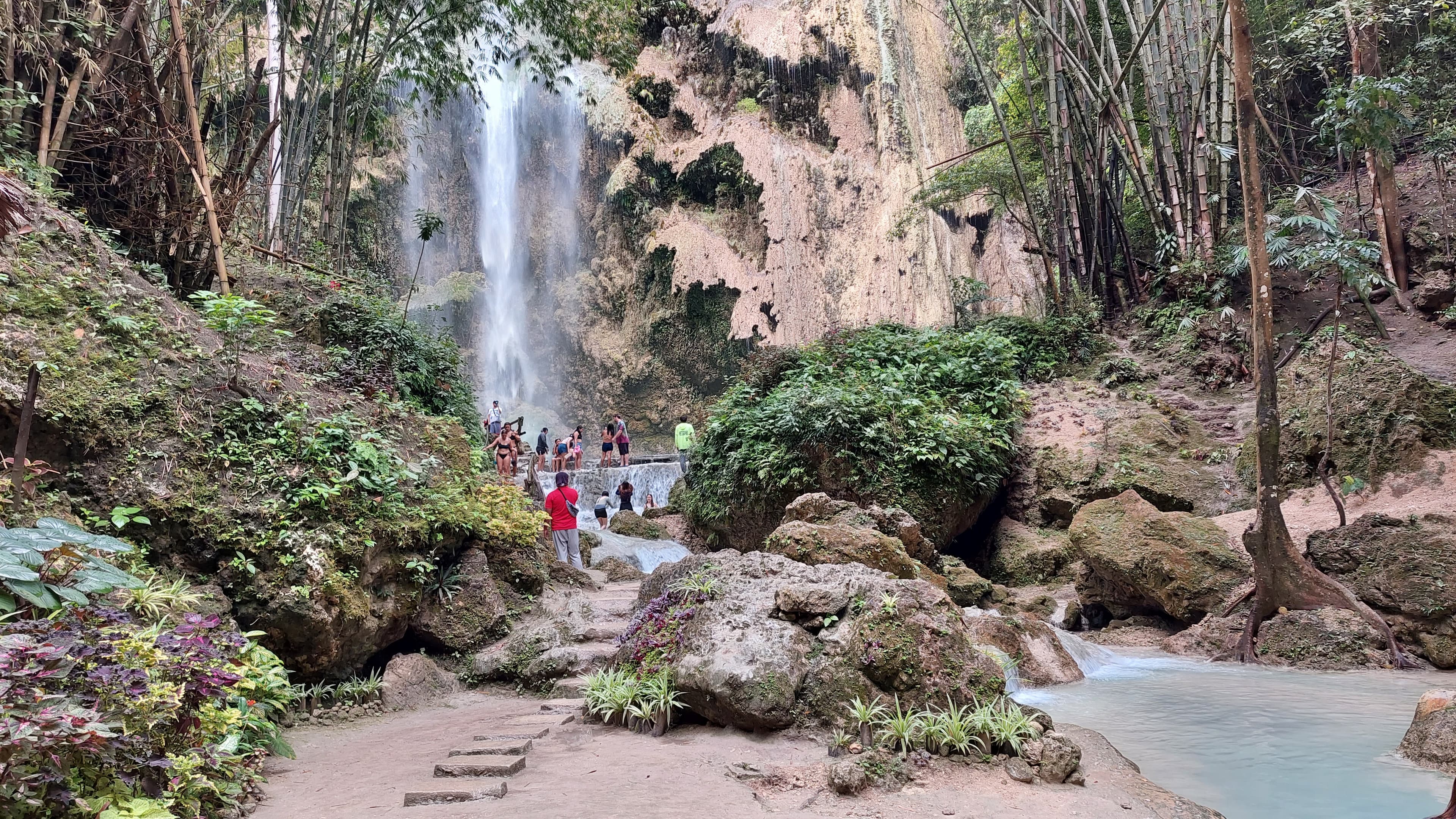 Wide curtain of water falling into a shallow pool at Tumalog Falls
